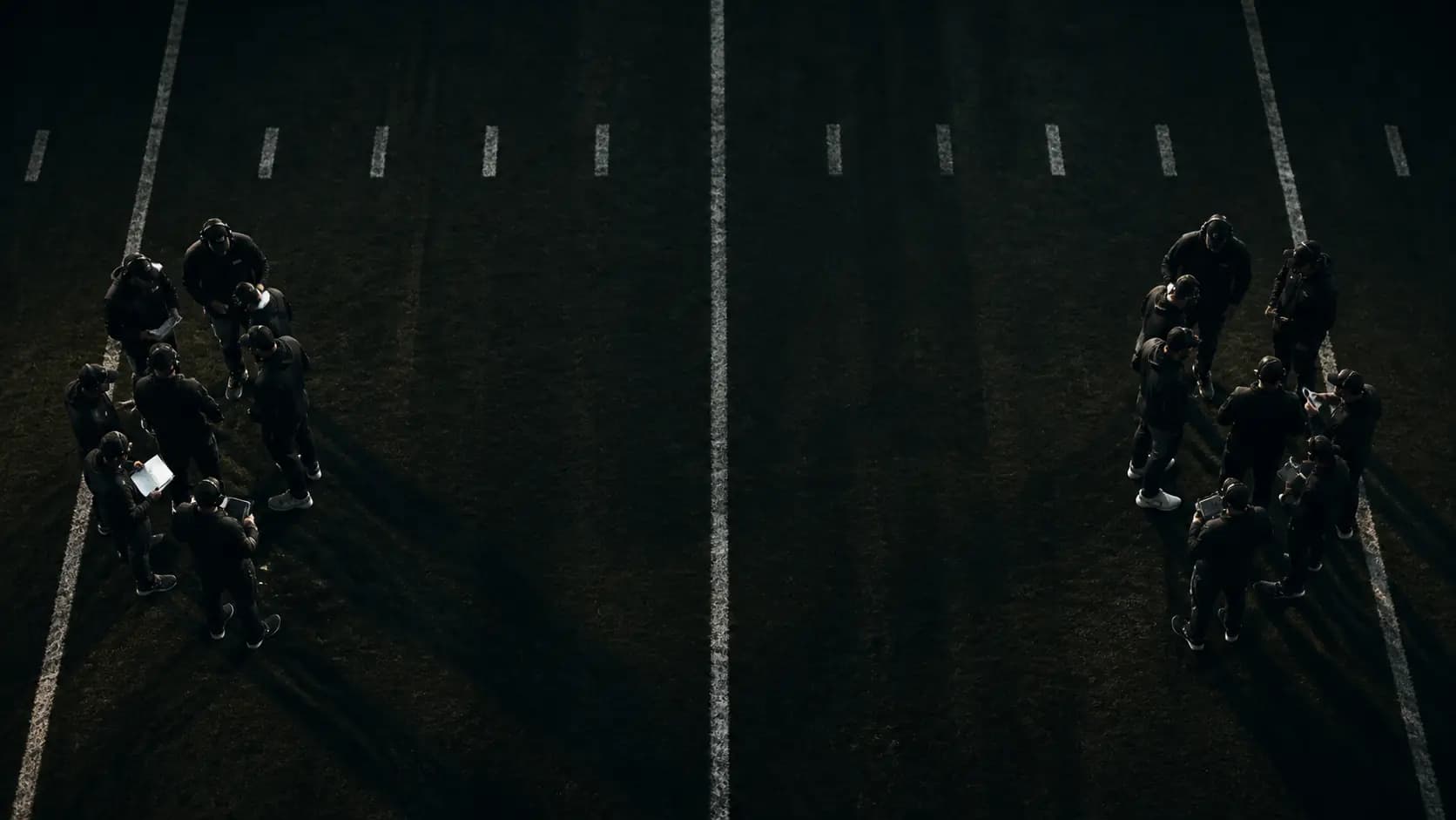 Two anonymous football coaching groups facing across a midfield seam from above